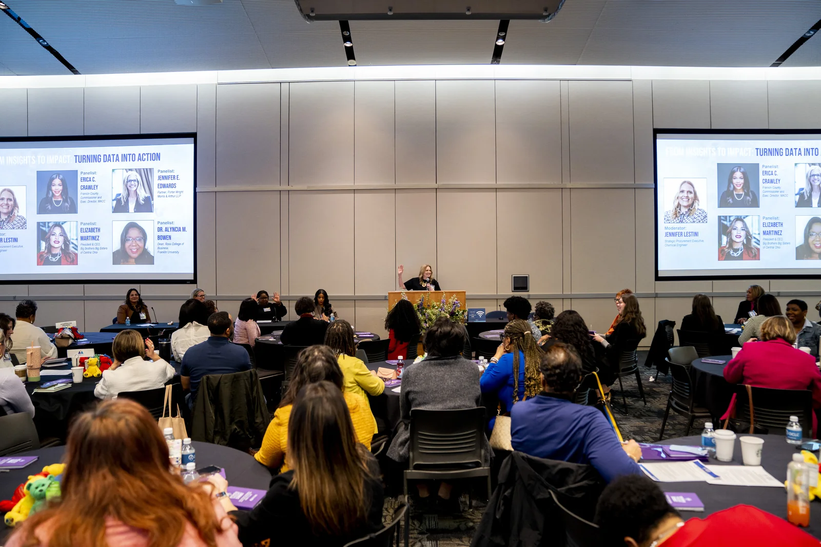 Wide Women in Thought Summit room environment showing tables, participants, and the presentation system at event scale.