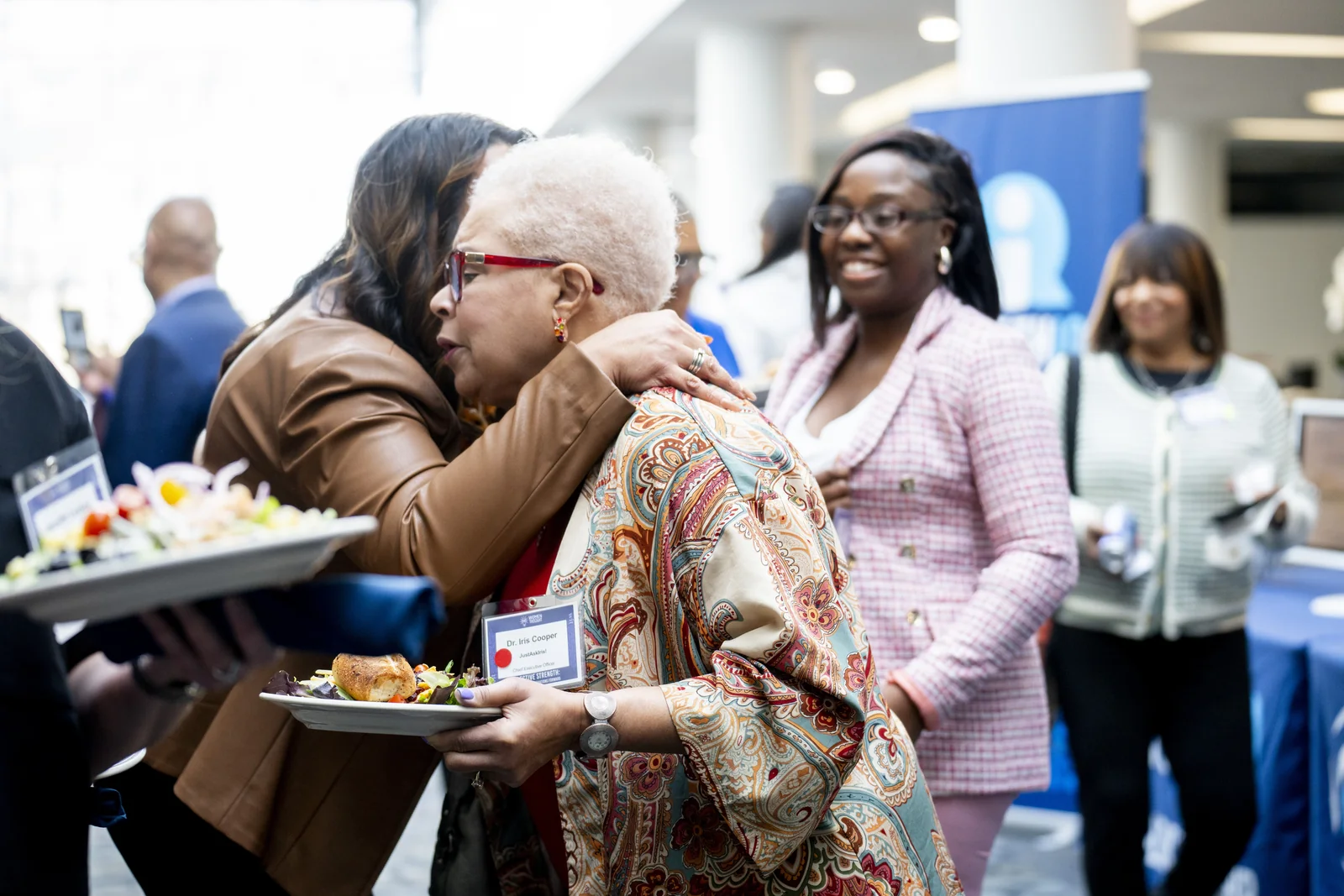 Women greeting one another during the Women in Thought Summit, showing connection and informal conversation inside the event.
